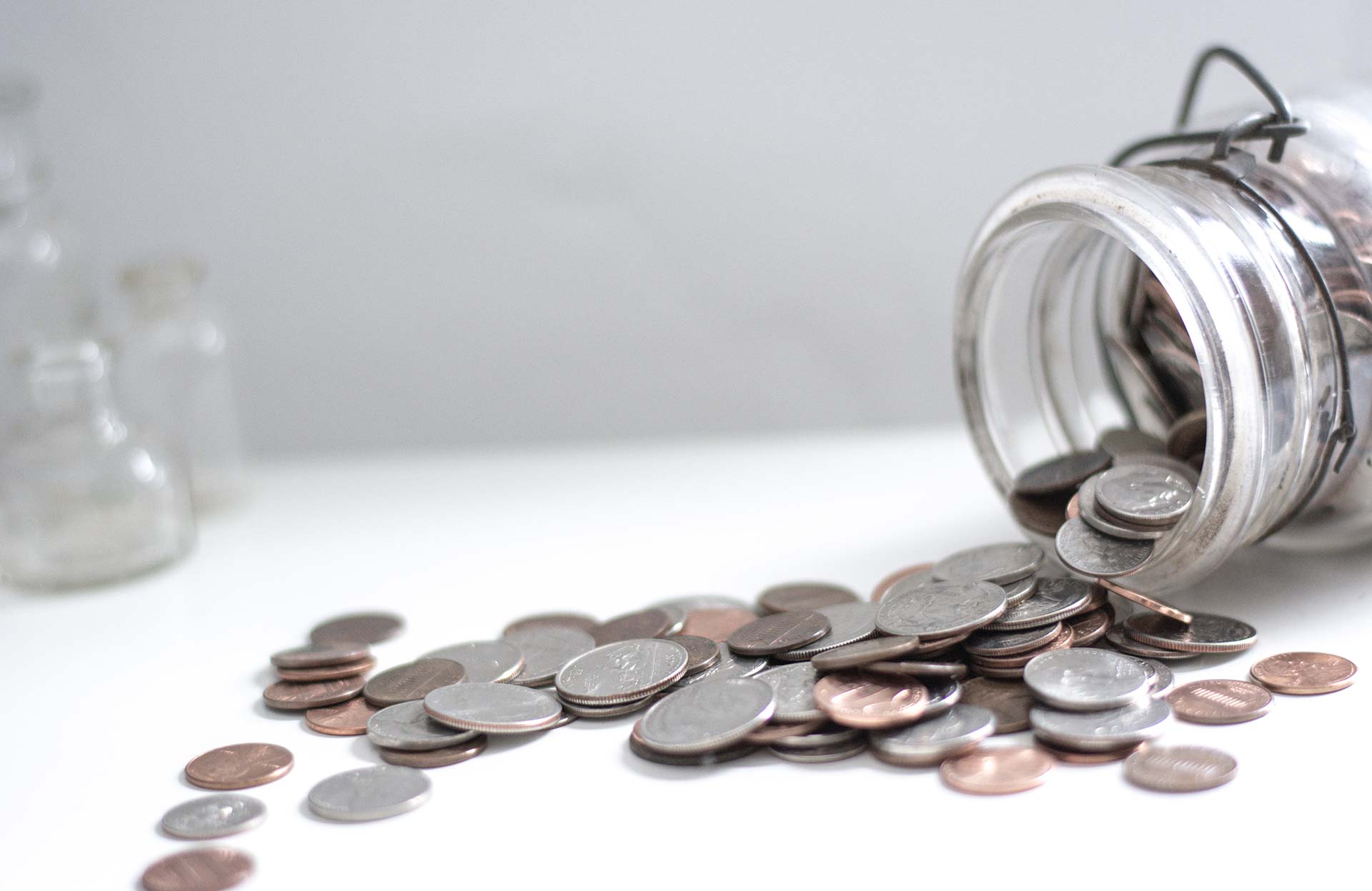 Spilled jar with scattered coins on table.