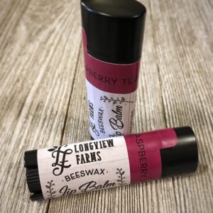 Two beeswax lip balms from Longview Farms on a wooden surface.