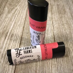Two lip balm tubes labeled "Longleaf Haze" on a wooden surface.