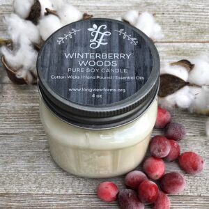 Winterberry Woods scented candle in a glass jar with cotton and berries.