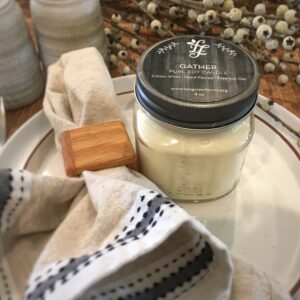 A jar of creamy lotion with a wooden applicator on a tray.